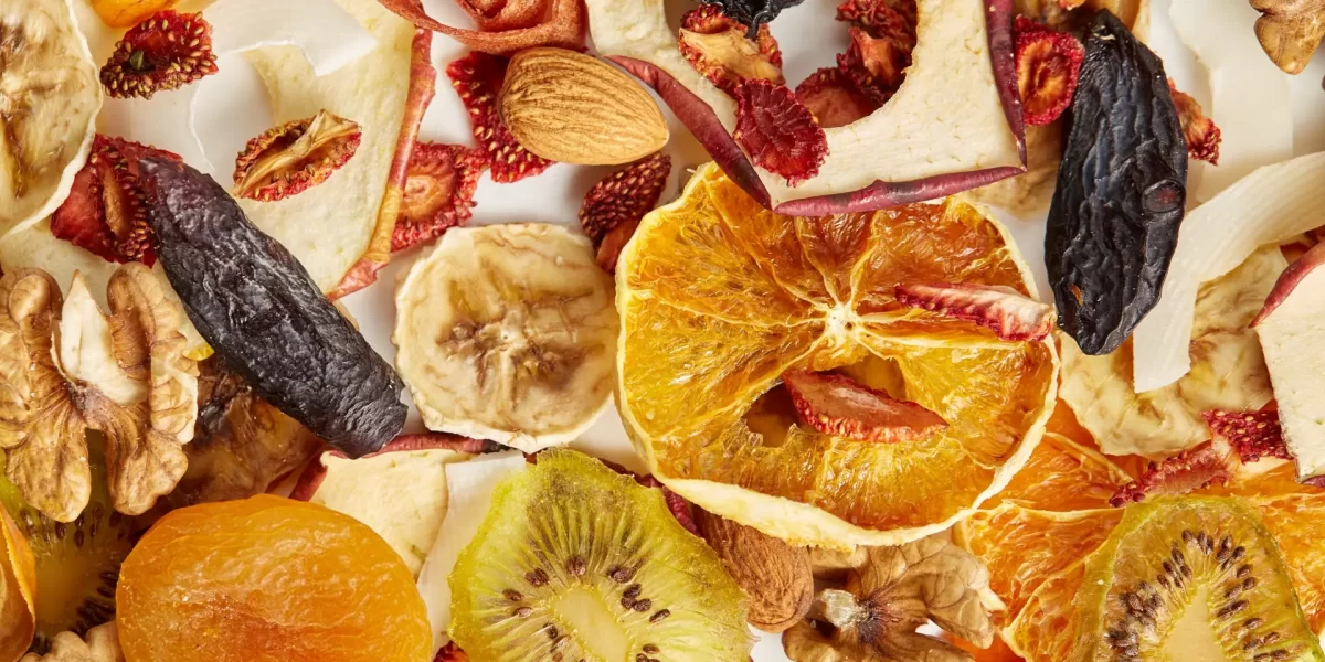 Close up of almonds, dried apricot, raisins, walnuts, dried apples, orange, bananas and kiwi on white background. Concept of organic healthy assorted dried fruit for snacks.